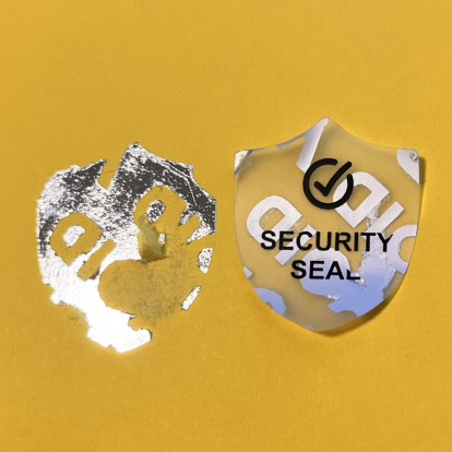 "SECURITY SEAL" VOID nyomot hagyó biztonsági matrica 25x30 mm pajzs forma, matt ezüst