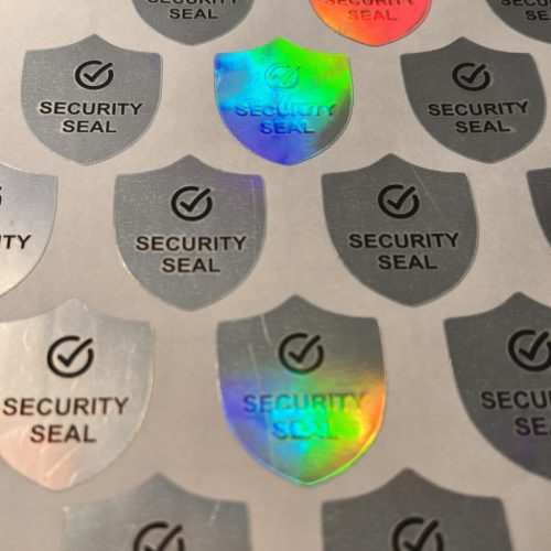 "SECURITY SEAL" VOID nyomot hagyó biztonsági matrica 25x30 mm pajzs forma, matt ezüst