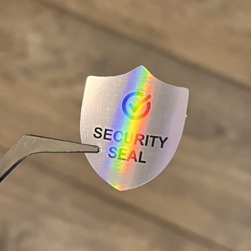 "SECURITY SEAL" VOID nyomot hagyó biztonsági matrica 25x30 mm pajzs forma, matt ezüst