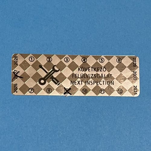 Pepita nyomot hagyó 6 éves (2026-2031) kétnyelvű felülvizsgálati biztonsági matrica 60x20 mm, fényes ezüst