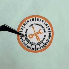   VOID nyomot hagyó 6 éves (2027-2032) felülvizsgálati biztonsági matrica narancs/fekete nyomtatással, 30 mm kör, matt fehér